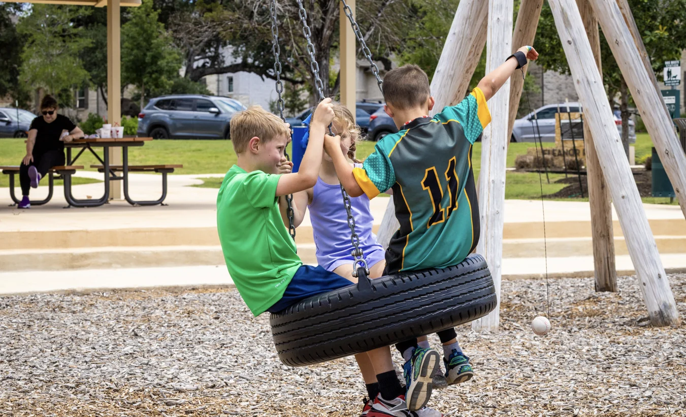 Young Veramendi residents in a tire swing at one of the Veramendi parks