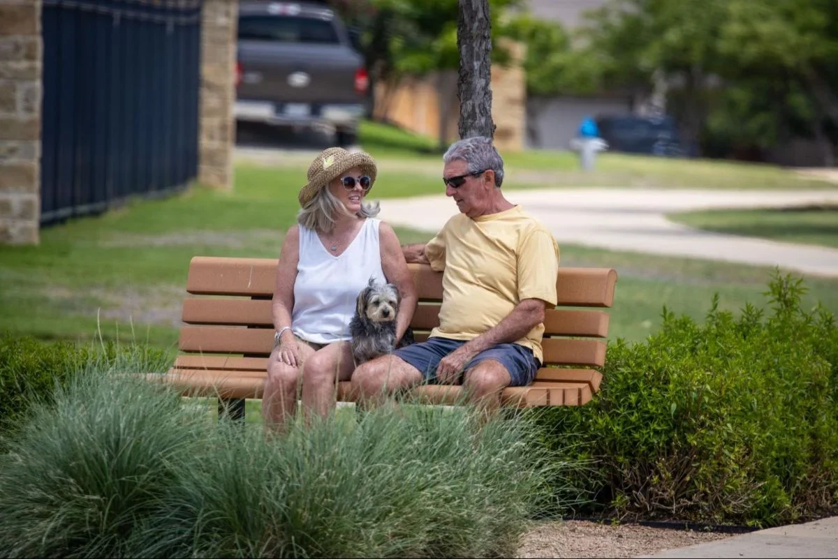 The Oscar at Veramendi residents sitting in a bench with their dog.